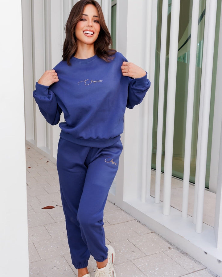 Blue 3-piece jogger set with sweatshirt, joggers, and inner top; features golden signature detail for elegance.
