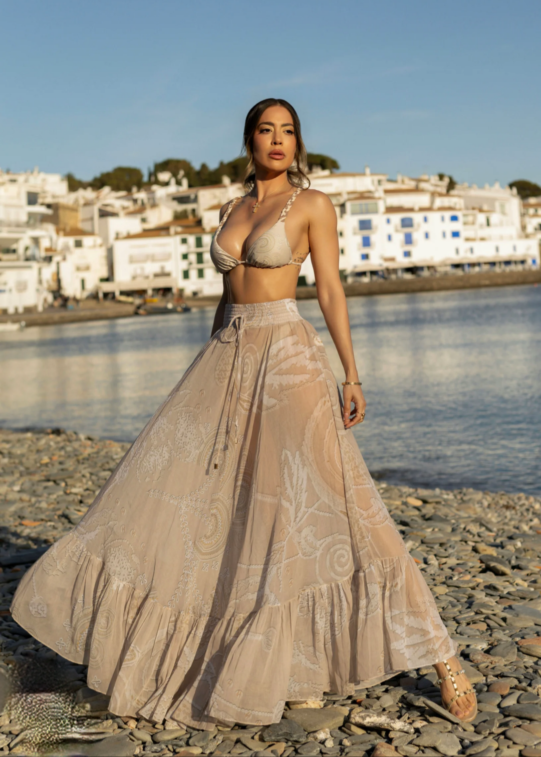 Beige sheer maxi skirt cover-up with paisley print on beach.