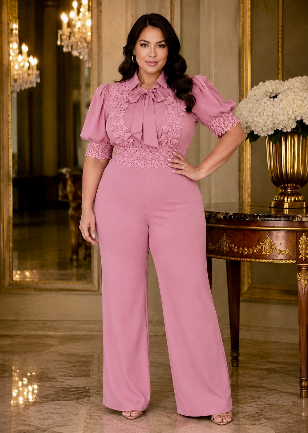 Curvy model wearing the Norma Pink Organza Jumpsuit featuring sheer organza sleeves, flattering high waist and elegant wide-leg pants.

