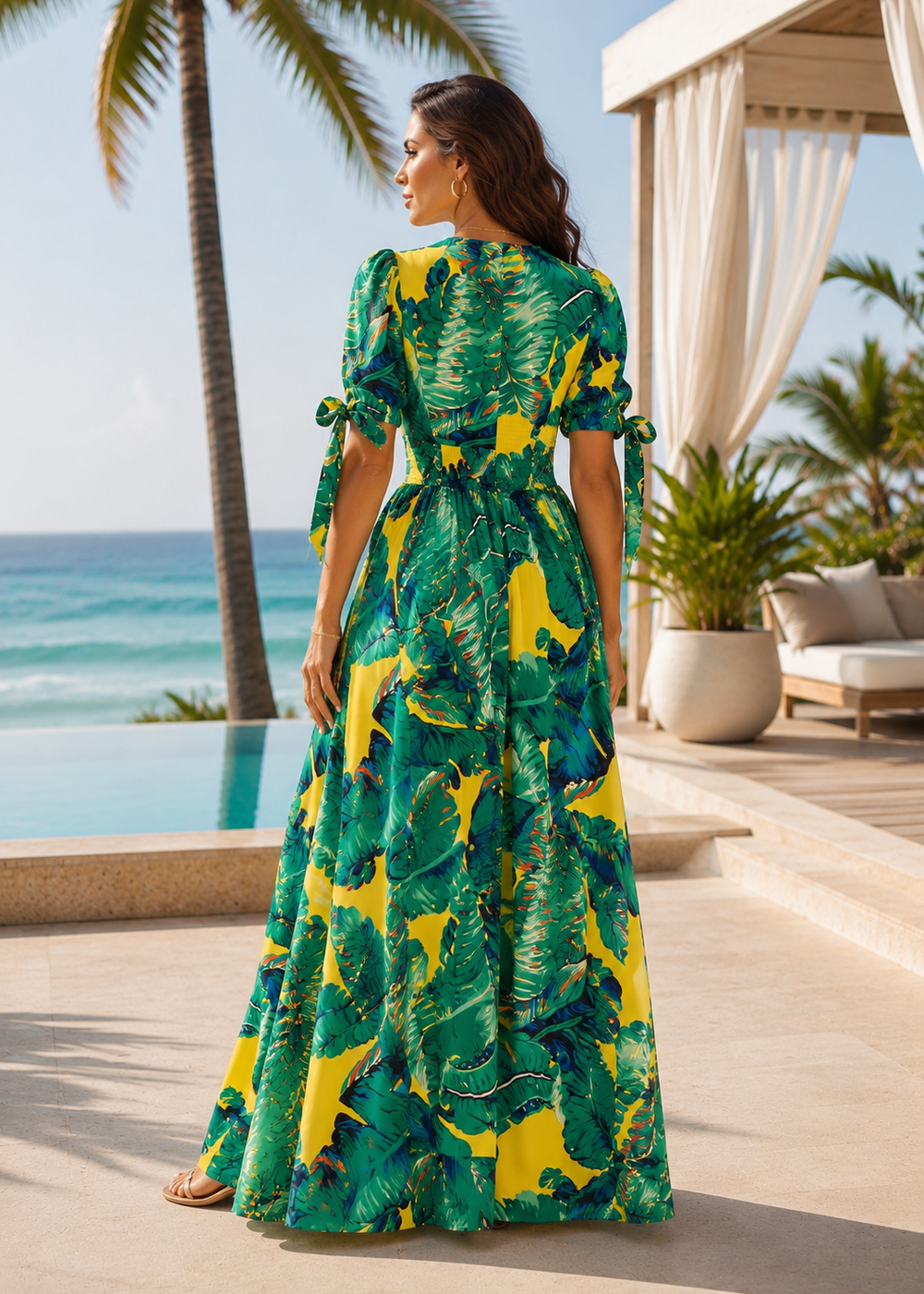 Back view of the Venice Beach tropical print maxi dress featuring short sleeves with tie details and a flowing maxi silhouette at an elegant oceanfront luxury resort.