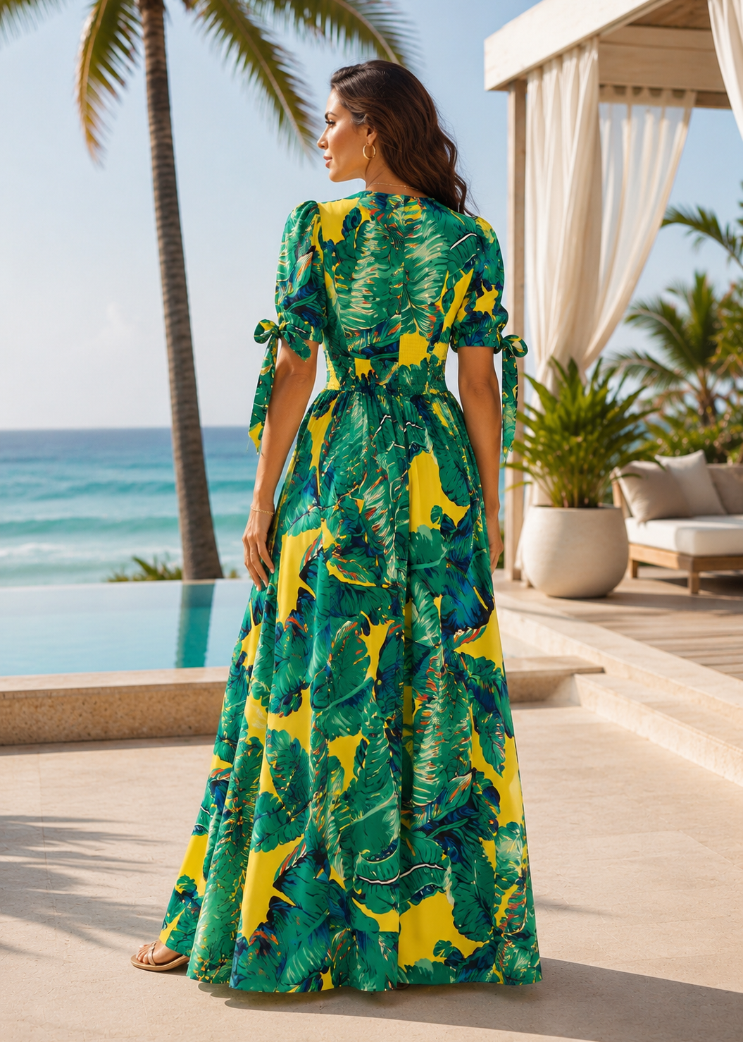 Back view of the Venice Beach tropical print maxi dress featuring short sleeves with tie details and a flowing maxi silhouette at an elegant oceanfront luxury resort.