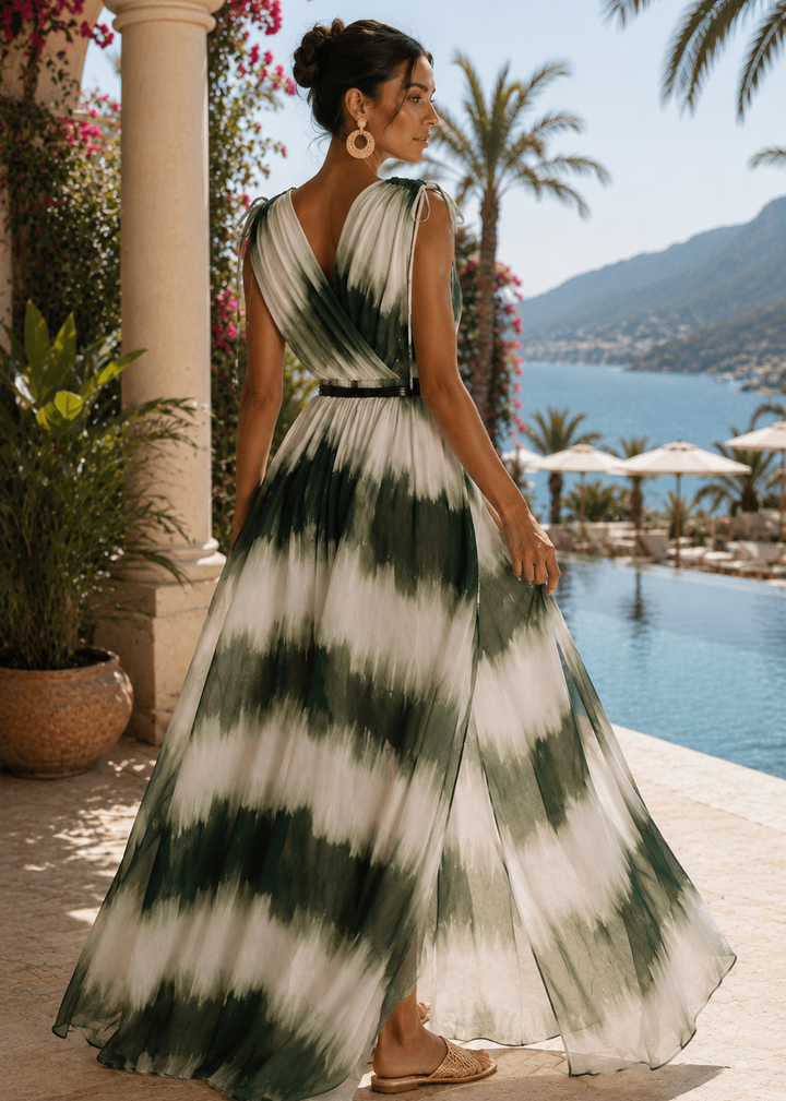 Side view of the YAIMA green tie-dye maxi dress showcasing the dramatic side cutout, flowing sheer fabric, double front slits, faux leather rope belt, and elegant luxury resort backdrop.