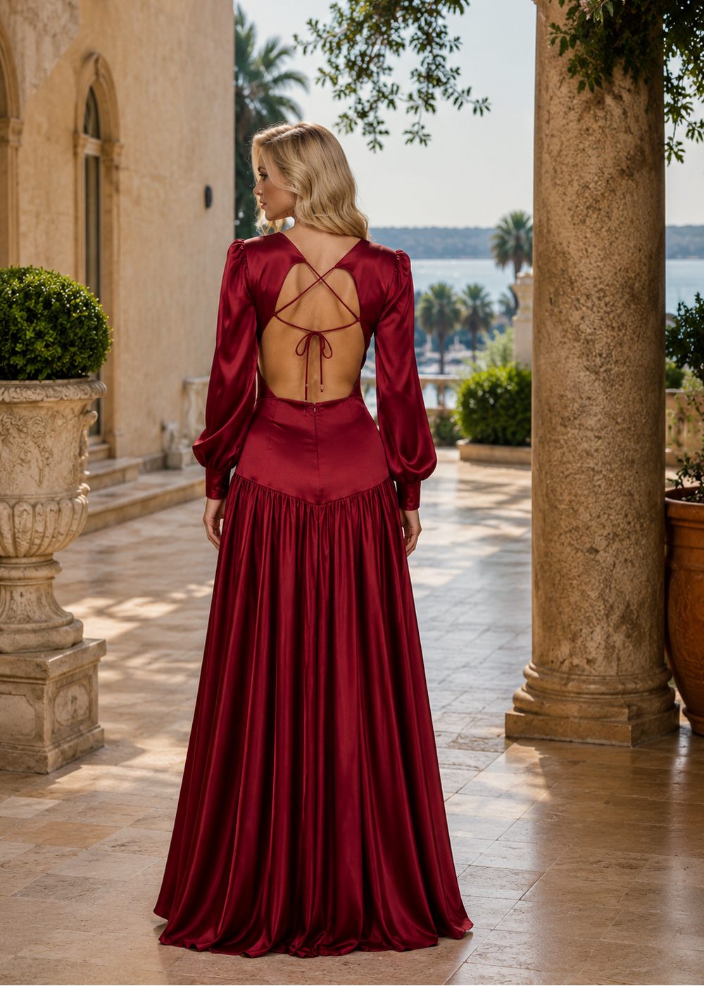 Woman wearing the Mykonos Red Ruby Satin Maxi Dress featuring luxurious satin fabric, elegant long sleeves, open-back design and flowing silhouette for weddings and formal occasions